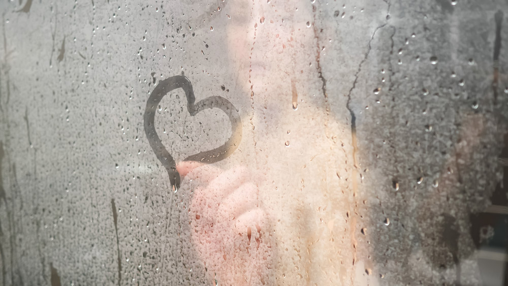 photo of person in steam shower drawing heart on bathroom glass
