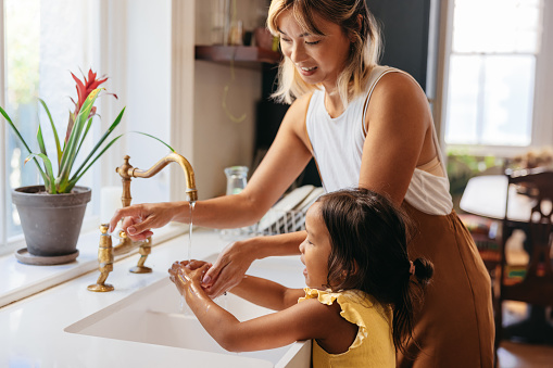 photo of woman and child washing hands over sink